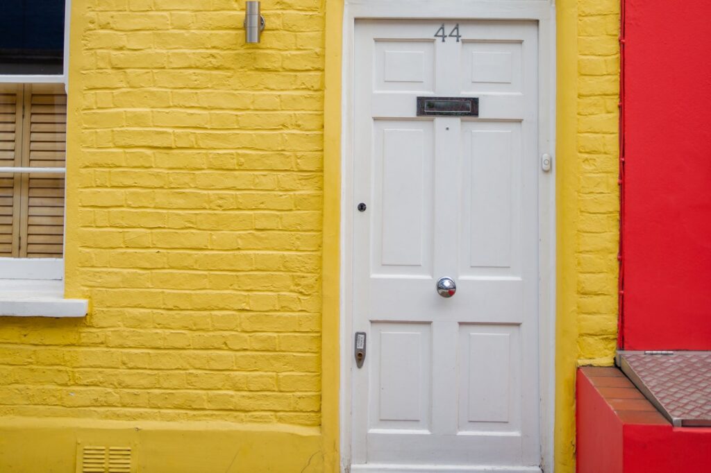 In front of a small door of a yellow and small brick flat.