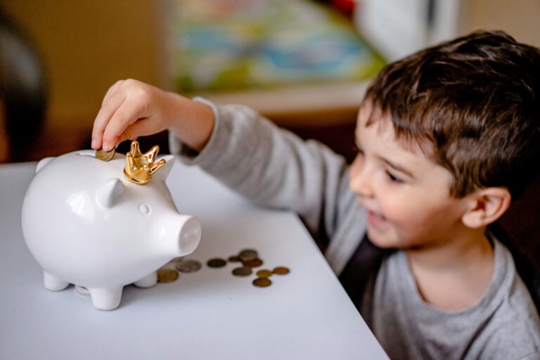 A kid is putting a coin into a piggy bank in the concept of saving money when moving to Hammersmith.