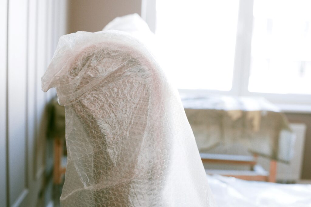 A cropped image of a couch and table wrapped in bubble wrap