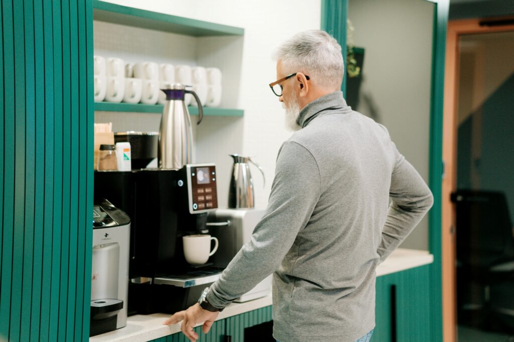 A male employee in the office pantry preparing a cup of coffee