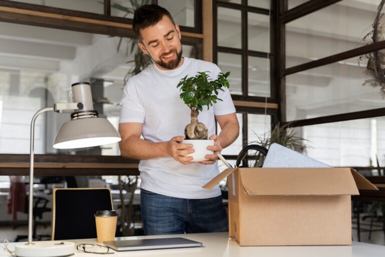 A male employee happily setting up his desk in the concept of 'How to Set Up a New Office After the Move to Hammersmith'.