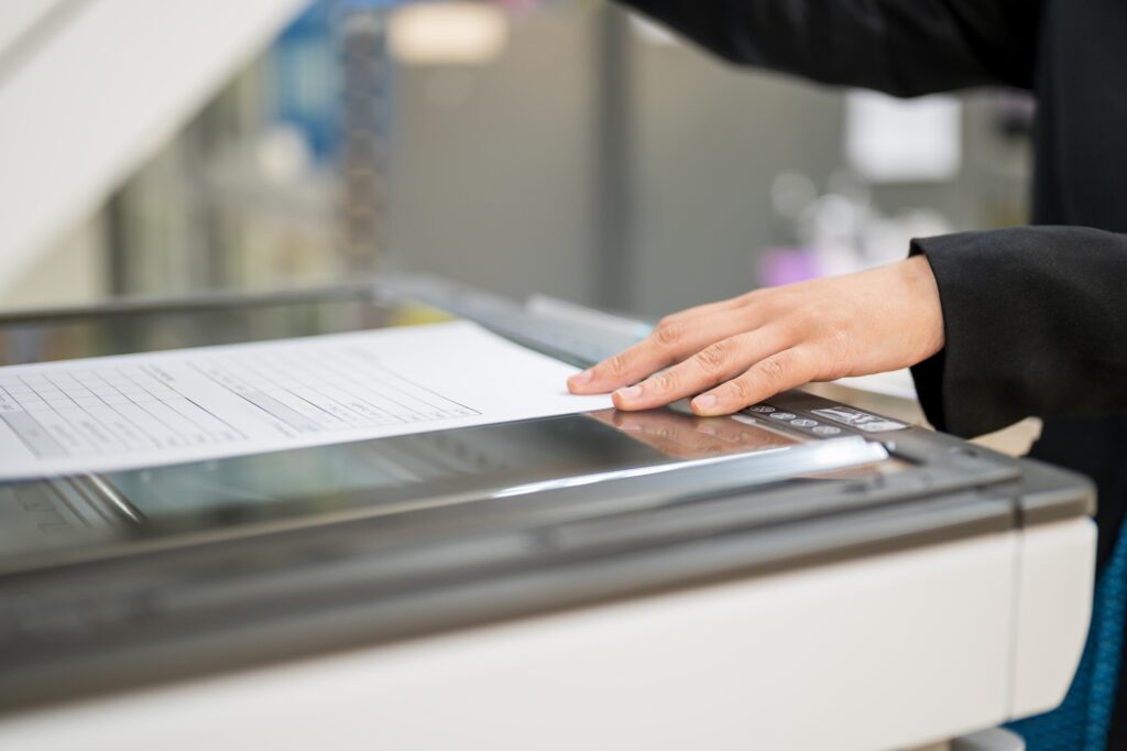 Cropped image of a female staff using a photocopier in the concept of 'How to pack office it equipment and electronics'.